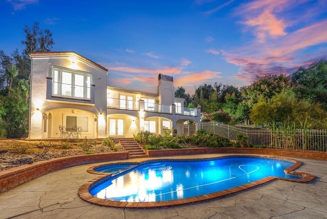 pool at dusk featuring an in ground hot tub and a patio