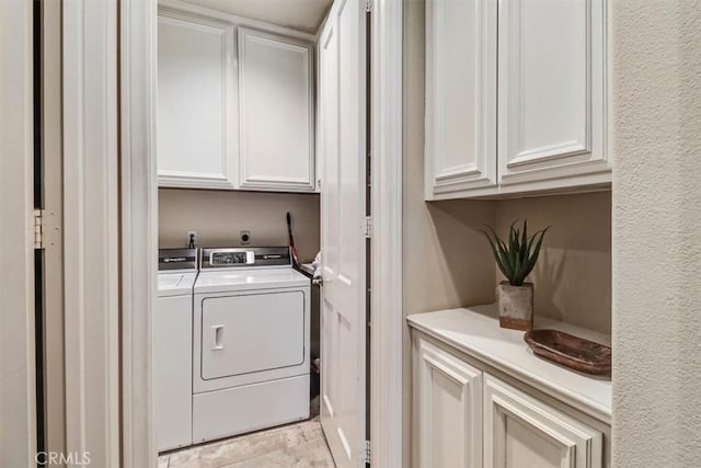 washroom featuring washing machine and clothes dryer and cabinets