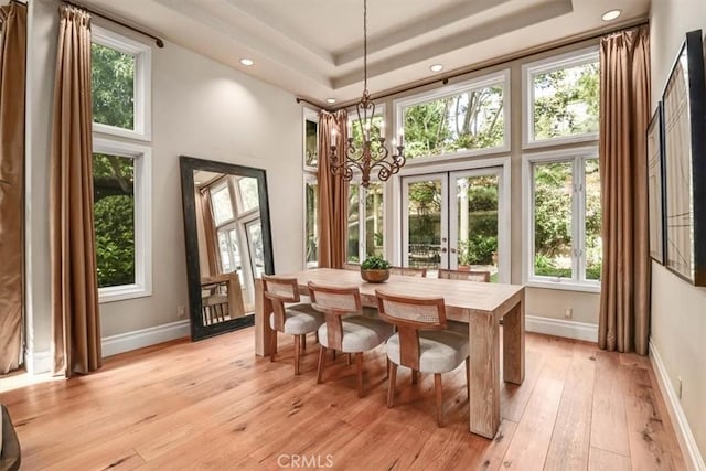 sunroom featuring a tray ceiling and an inviting chandelier