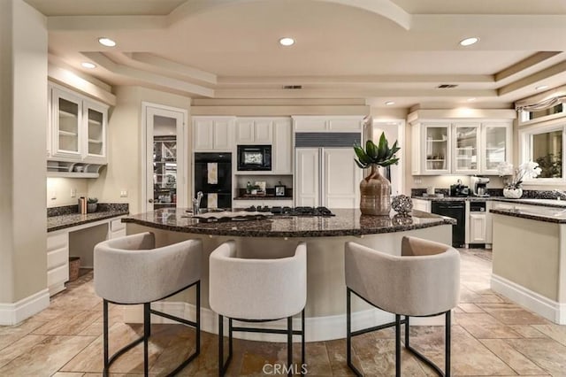 kitchen with a raised ceiling, white cabinetry, a center island, and black appliances