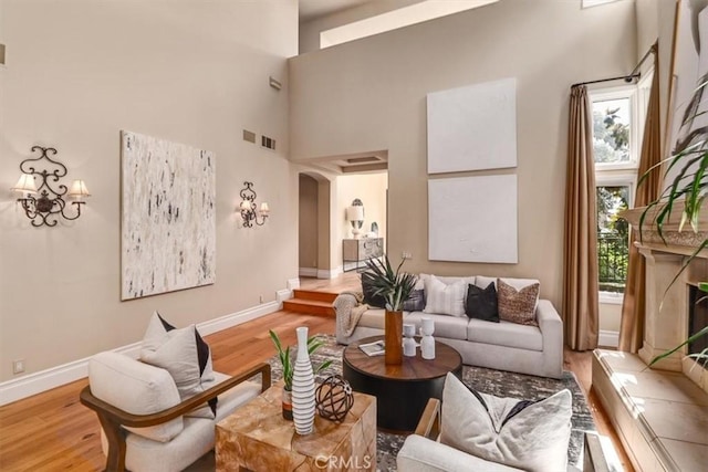 living room featuring a high end fireplace, a high ceiling, and light wood-type flooring