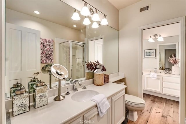 bathroom featuring hardwood / wood-style flooring, vanity, toilet, and a shower with shower door