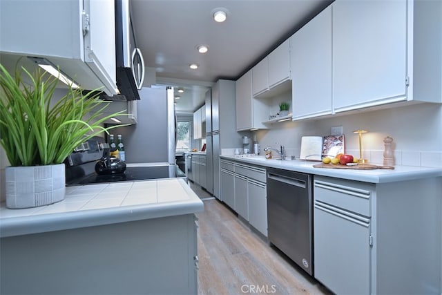 kitchen with light hardwood / wood-style flooring, appliances with stainless steel finishes, sink, and white cabinetry