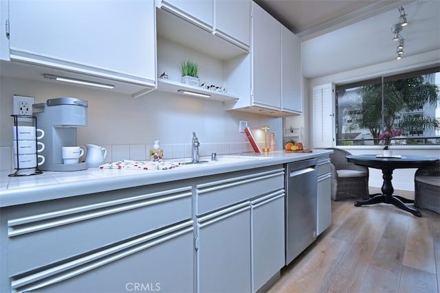 kitchen featuring white cabinets, light hardwood / wood-style flooring, tile counters, and stainless steel dishwasher