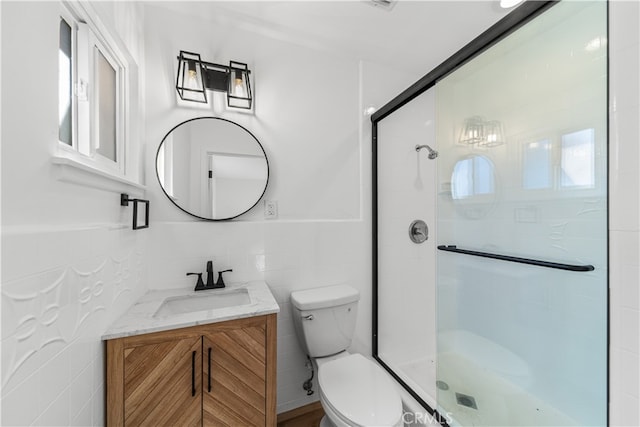 bathroom with vanity, tile walls, toilet, and an enclosed shower