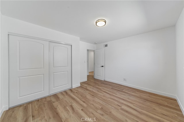 unfurnished bedroom with light hardwood / wood-style flooring and a closet