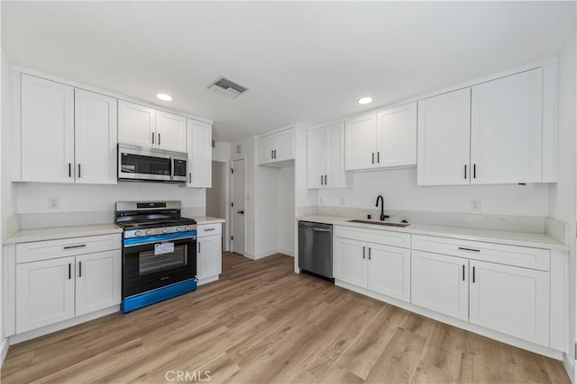 kitchen featuring white cabinets, appliances with stainless steel finishes, sink, and light hardwood / wood-style flooring