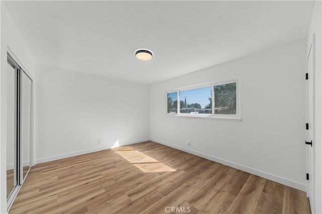 unfurnished bedroom featuring light hardwood / wood-style flooring and a closet