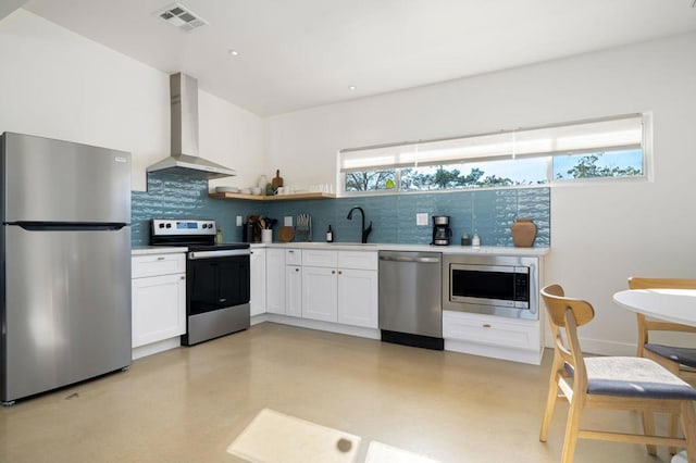 kitchen featuring sink, wall chimney range hood, backsplash, white cabinets, and appliances with stainless steel finishes