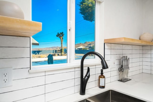 details with backsplash, light stone counters, and white cabinetry