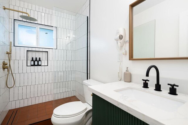 bathroom with tiled shower, vanity, and toilet