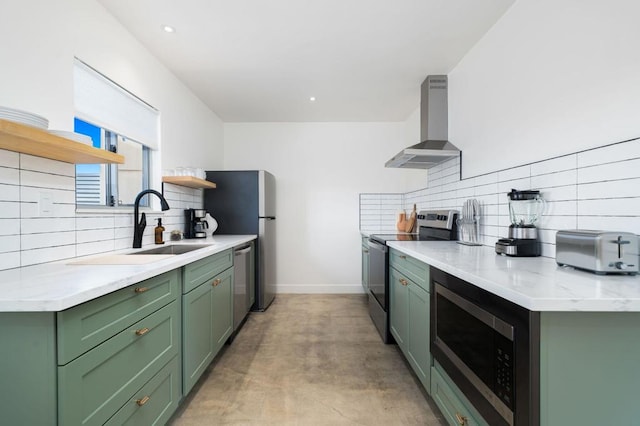 kitchen with sink, wall chimney exhaust hood, stainless steel appliances, green cabinets, and backsplash