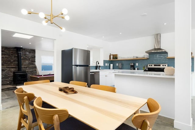 dining space featuring a wood stove, a notable chandelier, and sink