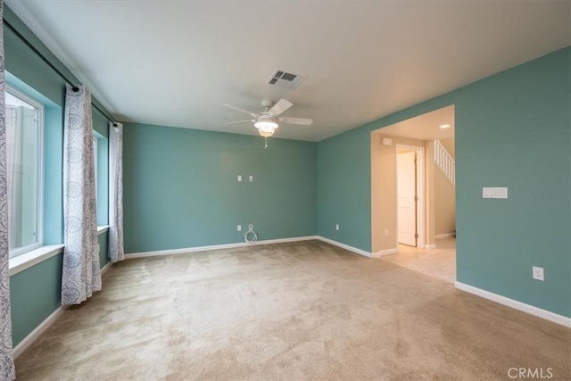 unfurnished room with light colored carpet, plenty of natural light, and ceiling fan