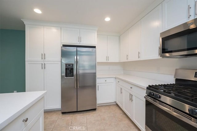 kitchen with stainless steel appliances, white cabinetry, and light tile patterned flooring