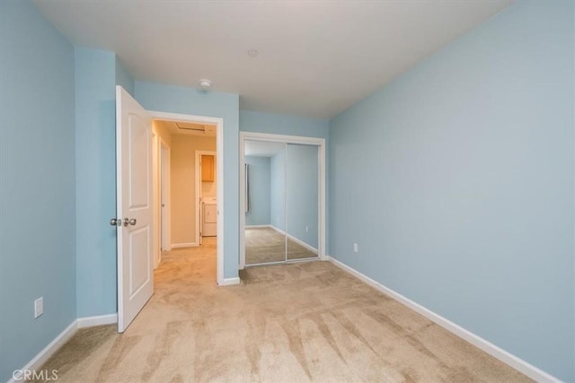 unfurnished bedroom featuring light carpet, washer / dryer, and a closet