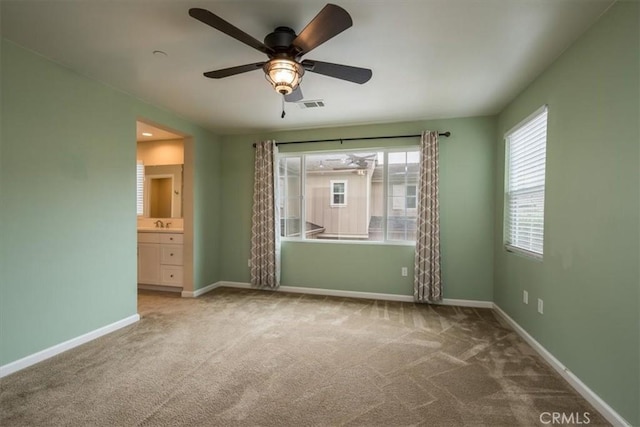 unfurnished bedroom with carpet flooring, ceiling fan, sink, and ensuite bath