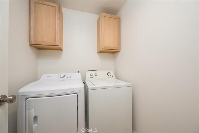 clothes washing area with cabinets and independent washer and dryer