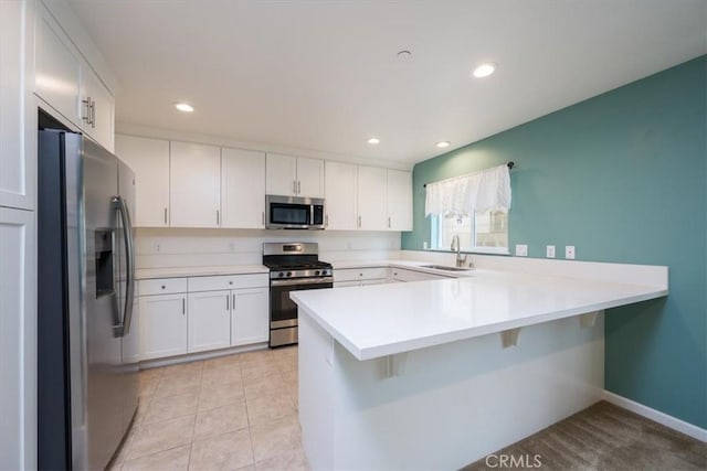 kitchen featuring white cabinetry, sink, kitchen peninsula, light tile patterned floors, and appliances with stainless steel finishes