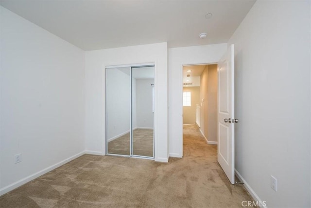 unfurnished bedroom with light colored carpet and a closet