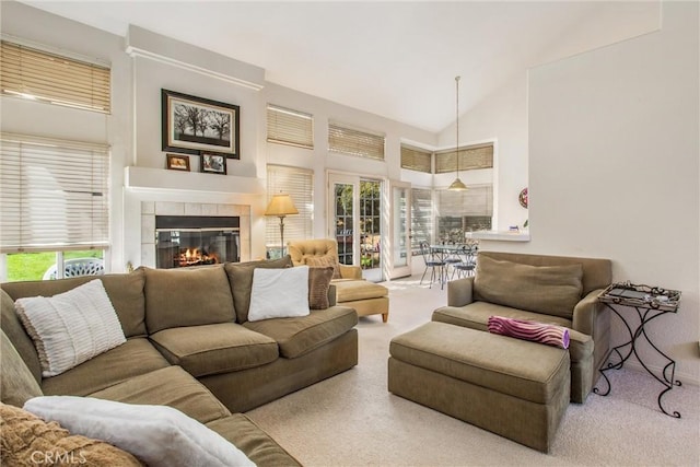 living room featuring a tile fireplace, light colored carpet, and high vaulted ceiling