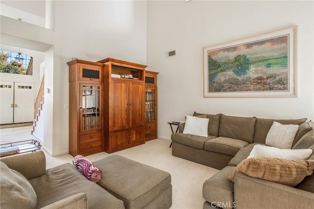 carpeted living room with a towering ceiling