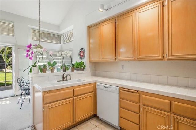 kitchen with tile countertops, dishwasher, sink, and vaulted ceiling