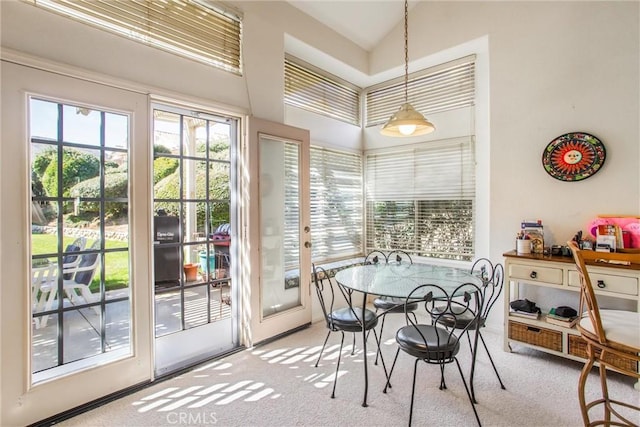 dining area with high vaulted ceiling and light colored carpet