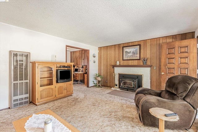 living room featuring a wood stove, wood walls, a textured ceiling, and light colored carpet