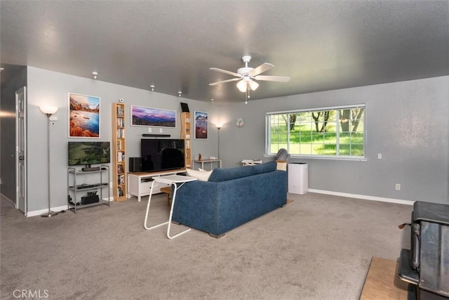 carpeted living area with a textured ceiling, baseboards, and ceiling fan