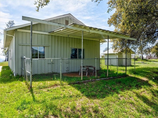 rear view of house with a lawn, board and batten siding, and fence