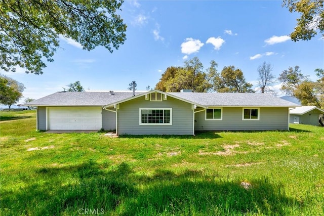 rear view of property with a lawn, a garage, and driveway