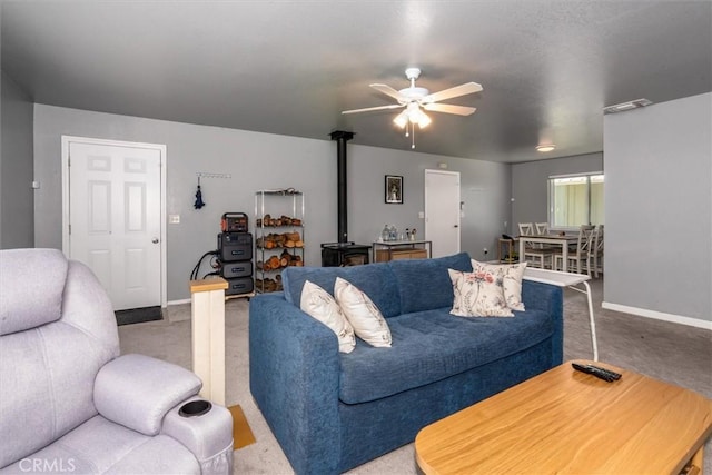 living area with a ceiling fan, baseboards, carpet, and a wood stove