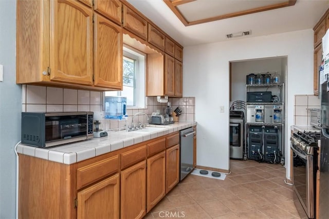 kitchen featuring visible vents, a toaster, decorative backsplash, appliances with stainless steel finishes, and a sink