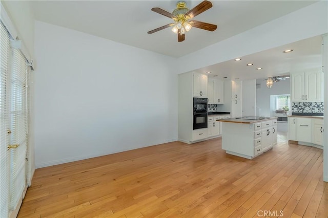 kitchen featuring white cabinetry, backsplash, black appliances, and light wood finished floors