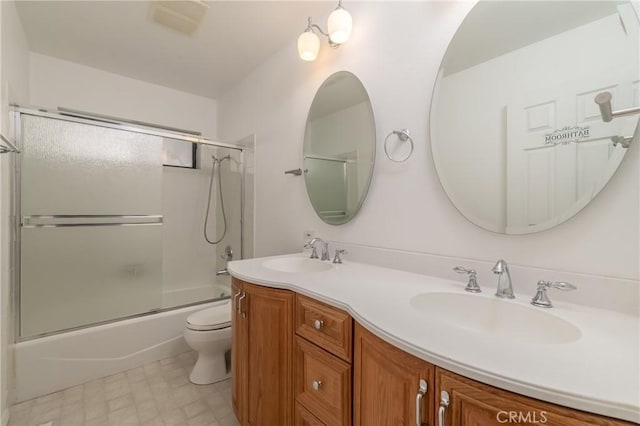 full bathroom featuring double vanity, toilet, combined bath / shower with glass door, and a sink