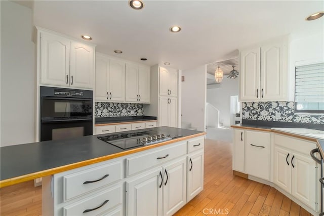 kitchen with white cabinets, black appliances, tasteful backsplash, and light wood finished floors