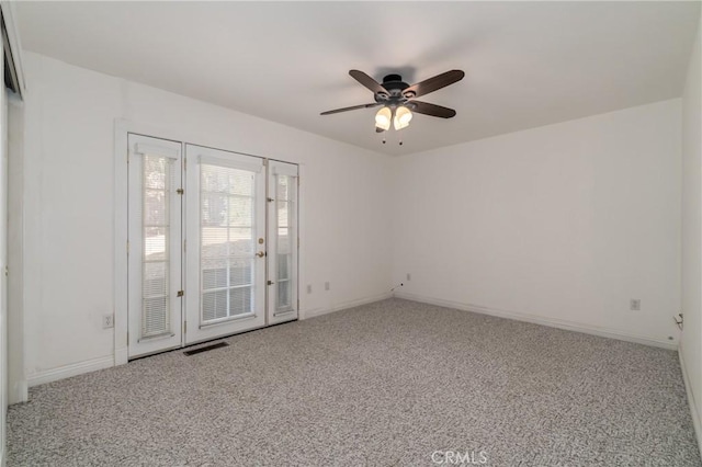 carpeted spare room with a ceiling fan, visible vents, and baseboards