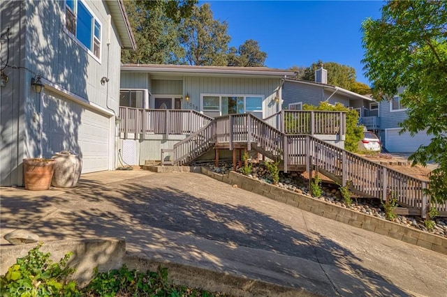 rear view of house featuring driveway, a garage, and stairway