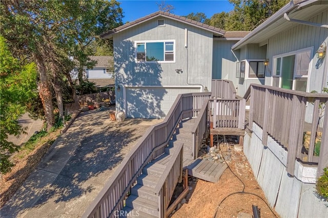 back of house featuring a garage, stairway, and concrete driveway