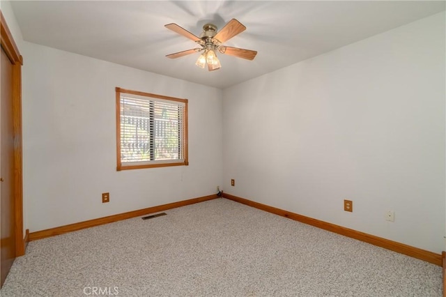 empty room with carpet floors, visible vents, baseboards, and a ceiling fan