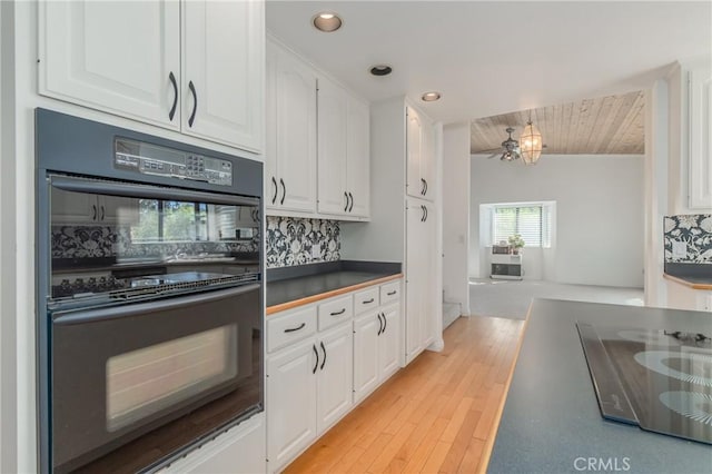 kitchen with dobule oven black, decorative backsplash, and white cabinetry