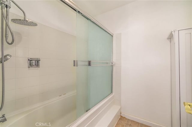 full bath featuring baseboards and bath / shower combo with glass door