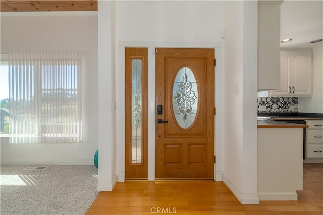 foyer featuring light wood-style floors, visible vents, and baseboards