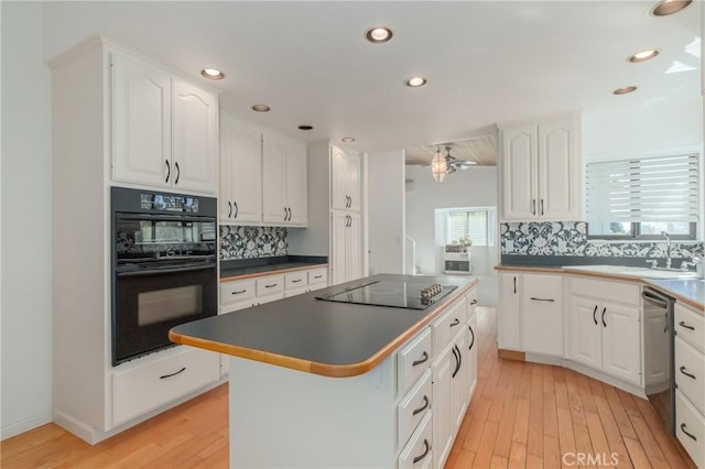 kitchen featuring black appliances, light wood-type flooring, a center island, and white cabinets