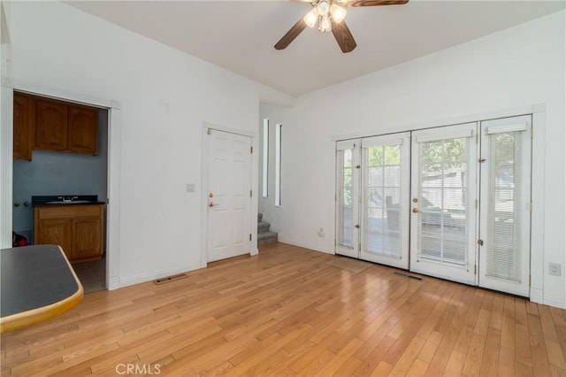 unfurnished living room with visible vents, baseboards, light wood-style flooring, ceiling fan, and stairs