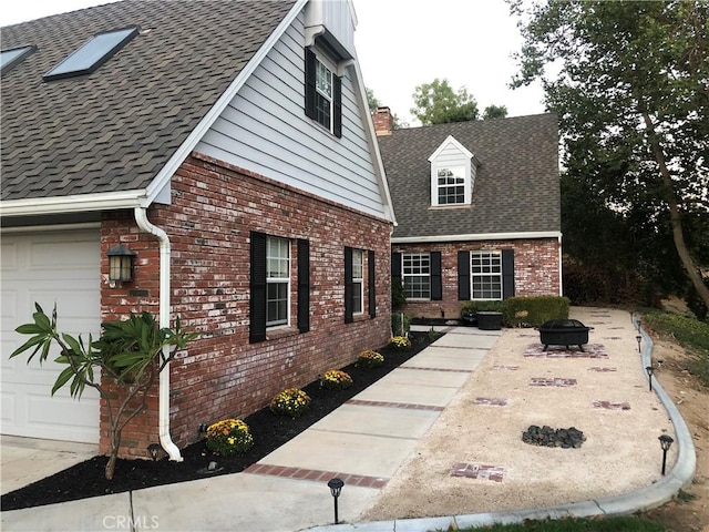 view of home's exterior featuring a garage and an outdoor fire pit