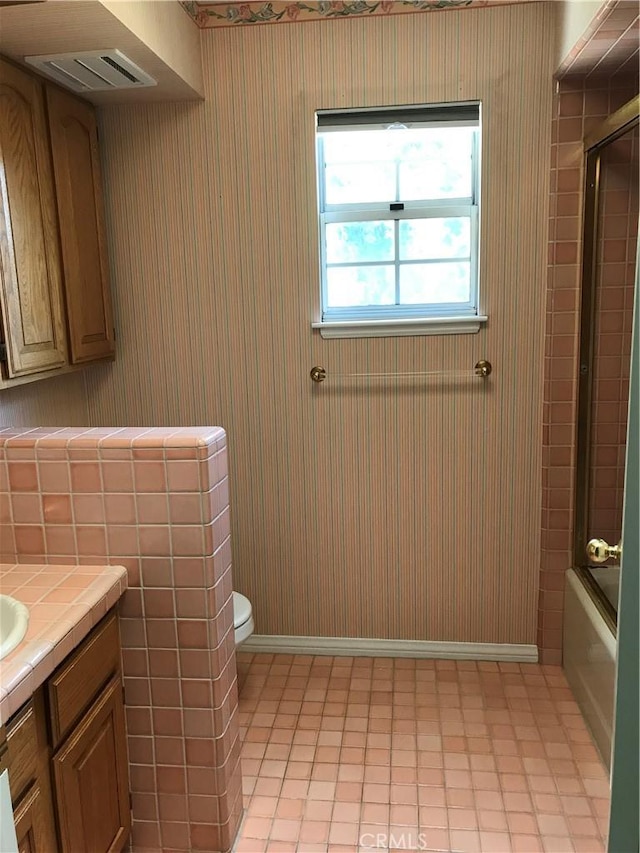 full bathroom featuring vanity, toilet, and enclosed tub / shower combo