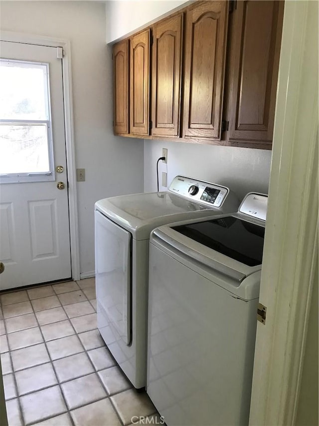 clothes washing area with cabinets, independent washer and dryer, and light tile patterned floors