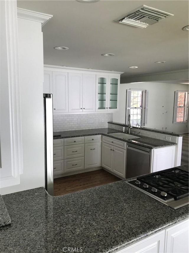 kitchen with white cabinets, sink, dark hardwood / wood-style flooring, kitchen peninsula, and stainless steel appliances